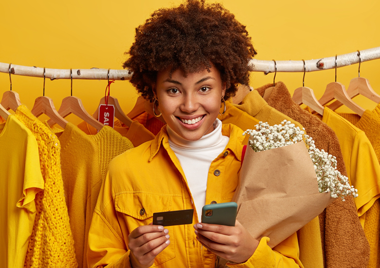 femme souriante dans un magasin de vêtements jaunes